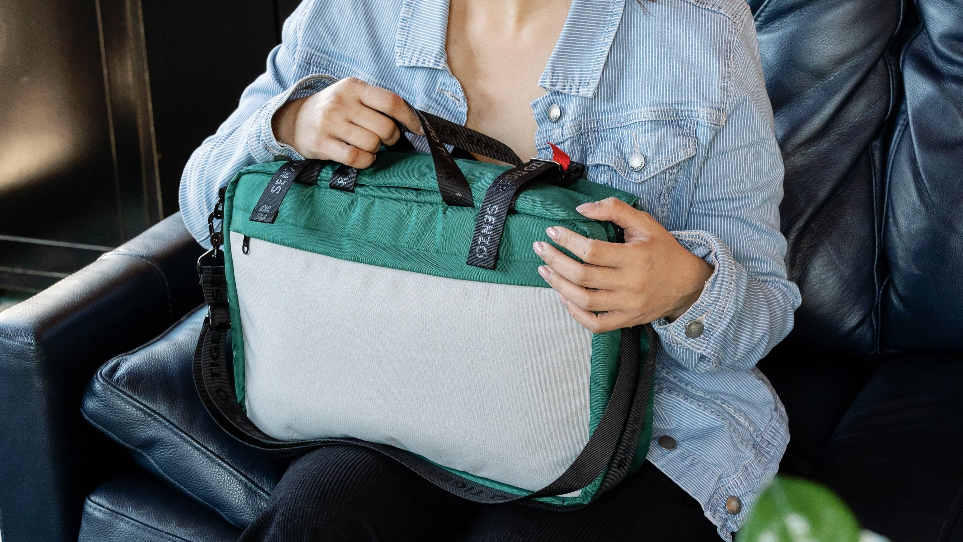 Woman sitting on a couch with a green version of the bag on her lap.