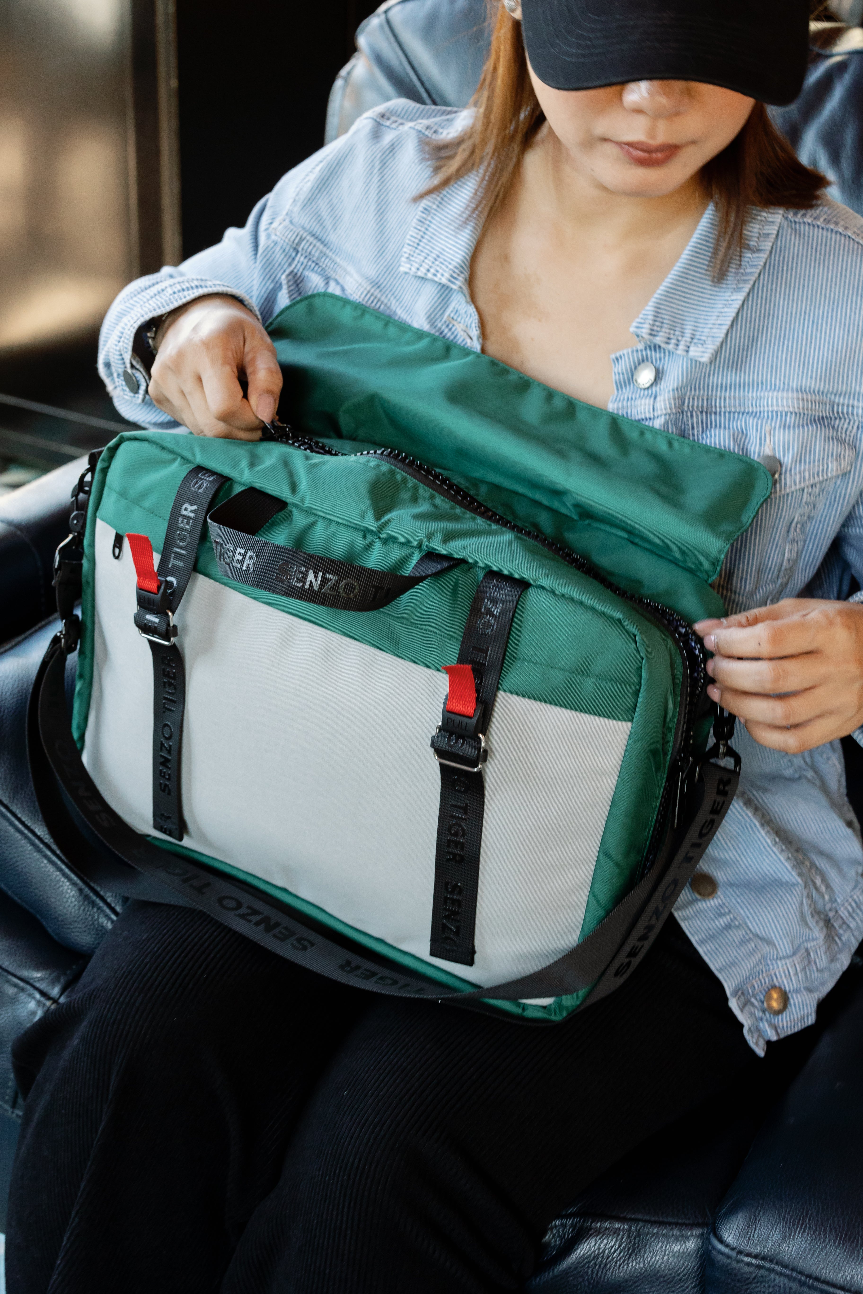 The same woman in a demin jacket is opening up her green bag. You can see how the bag opens up. You have to unbuckle the Fidlocks, pull up the flap, and then unzip the main compartment. 