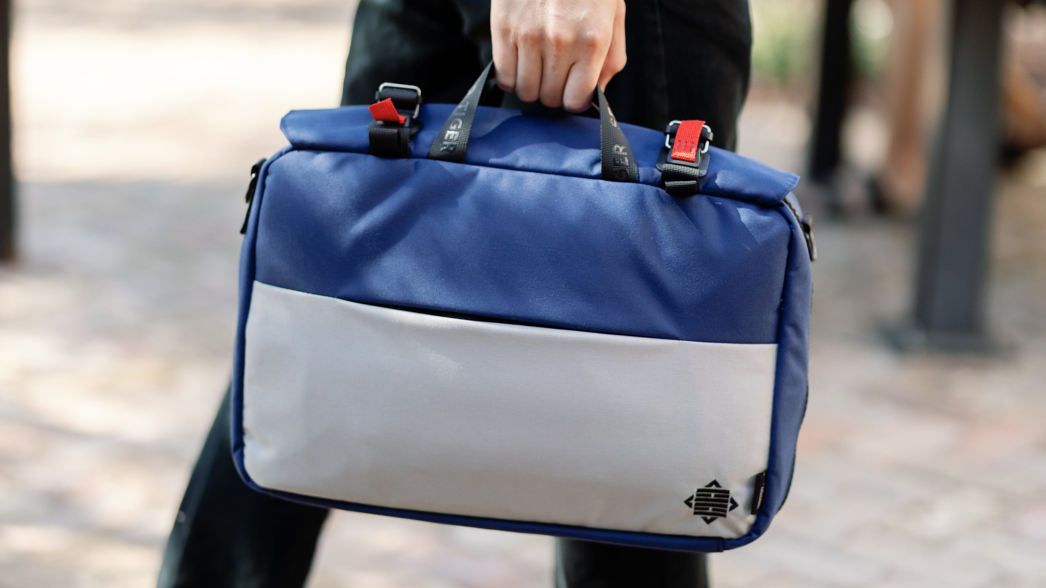 Front view of the blue and gray briefcase. Man is walking with it. 